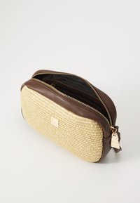 Borsa cosmetica in pelle marrone e paglia intrecciata con chiusura a zip, caratterizzata da un'etichetta dorata e una superficie testurizzata. All'interno è presente un tessuto nero.