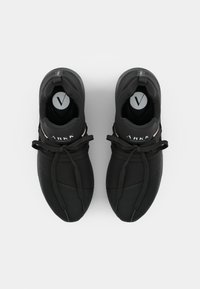 Black athletic shoes with a textured upper, rounded toe, and elastic laces. Features a pink accent stripe and logo on the heel.