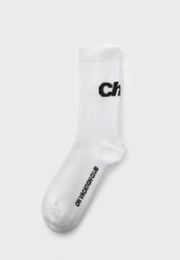 Valge puuvillane lühike sokk, mille ülaserval on must trükitud tekst "Ch" ja talla ääres "ONV ACTION CLUB", ribatekstuuriga.