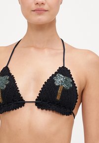 Top bikini in crochet nero con coppe triangolari, bordi scalloppati e decorazioni a forma di palma in paillettes su ciascuna coppa. Spalline regolabili.