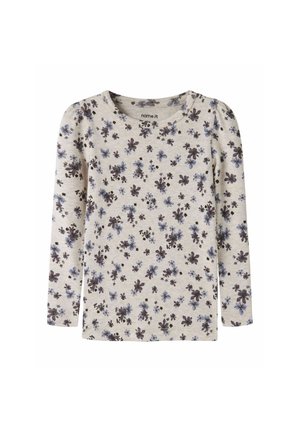 Chemise beige à manches longues avec petit imprimé floral bleu et violet foncé, encolure ronde et léger détail bouffant aux coutures des épaules.