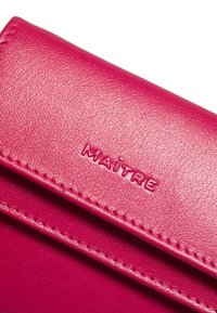 Portafoglio in pelle fucsia con superficie strutturata, logo "MAITRE" impresso e cuciture visibili lungo i bordi.