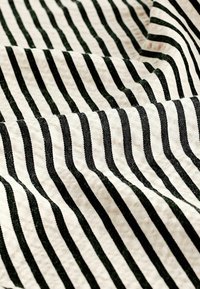 Randig tyg som har växlande svarta och off-white linjer, med en jämn textur och en lätt glans.