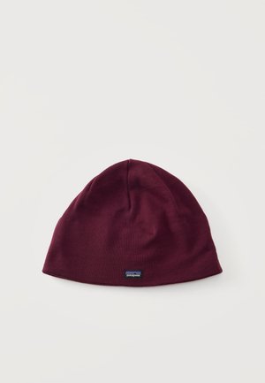 Berretto lavorato a maglia color granata con una piccola etichetta rettangolare con il logo Patagonia centrata vicino al bordo inferiore su uno sfondo chiaro.