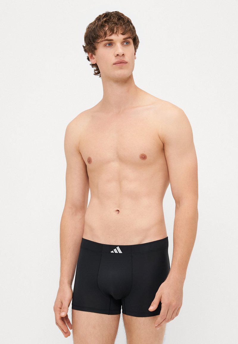 Boxers pretos ajustados, feitos de um material suave, com um logótipo branco da Adidas na cintura. Comprimento de perna curto.