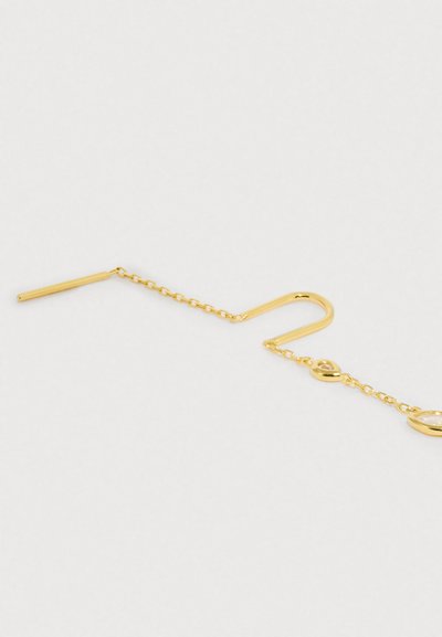 Brinco em tom dourado com design de gancho curvo longo, ligado por uma corrente delicada a detalhes ovais com acabamento suave.