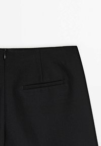 Pantalons noirs ajustés en tissu lisse, dotés d'une poche arrière avec une finition discrète et d'une fermeture éclair invisible à la taille.