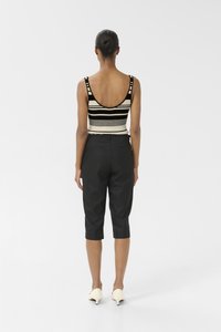 Sort cropped bukser parret med en sort og hvid stribet top uden ærmer. Glat stof, dyb halsudskæring og tætsiddende design.