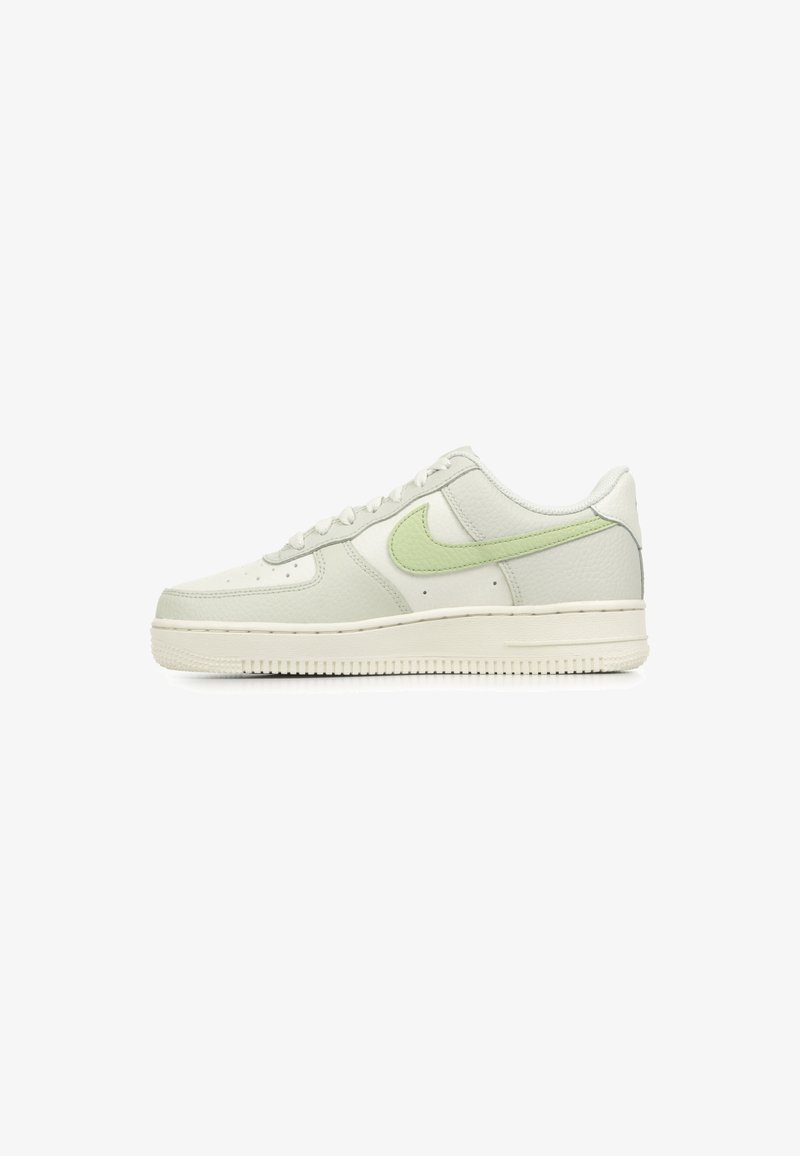 Witte leren sneakers met een lichtgroene swoosh. Laag model, ronde neus en getextureerde panelen. Dikke rubberen zool met grip.