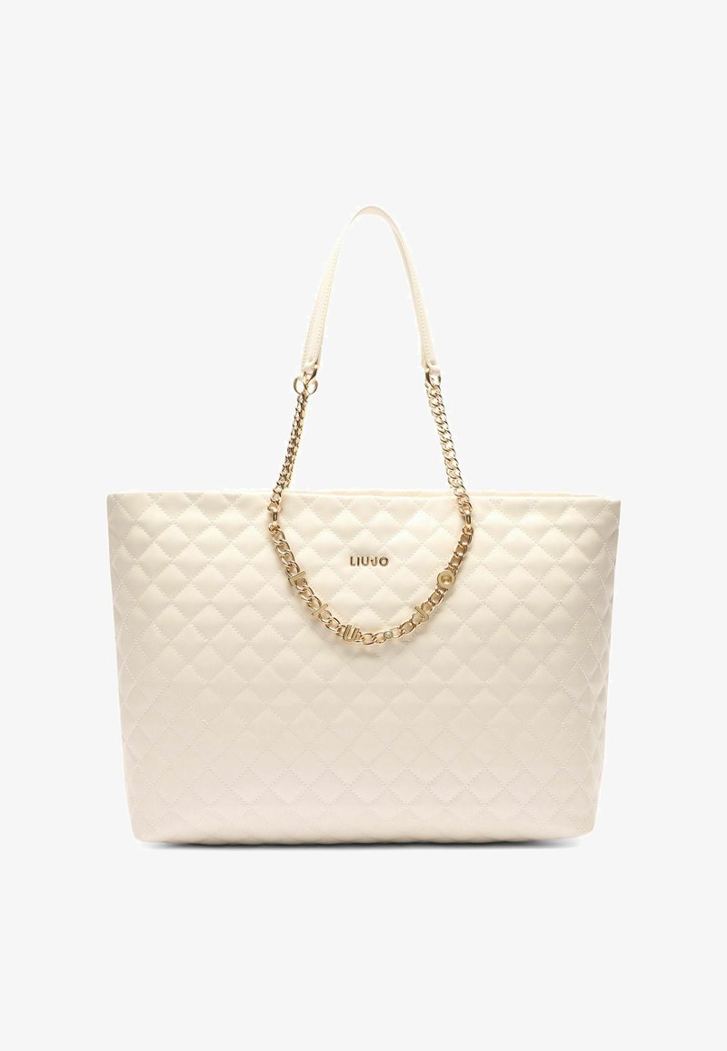 Sac fourre-tout matelassé crème avec une finition brillante, doté d'une accent en chaîne dorée et d'un logo subtil à l'avant. Poignées doubles pour le transport.