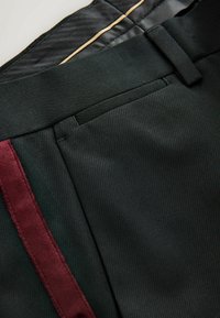 Schwarze Hosen mit feiner Nadelstreifenstruktur, versehen mit einem burgunderfarbenen Samtakzent an der Seite und einem glatten Satinbund.