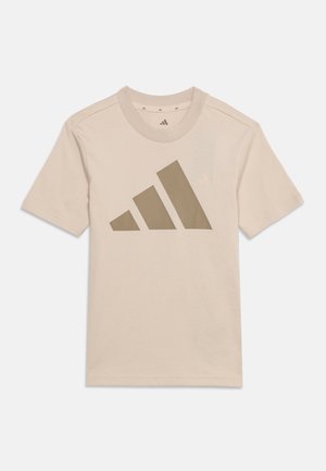 Tricou bej cu mâneci scurte și guler rotund, cu un logo mare, stilizat, Adidas în bej închis pe față.