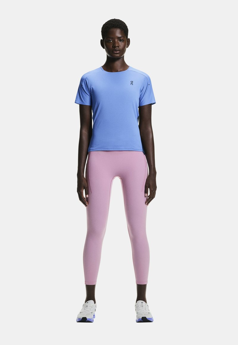 T-shirt de sport bleu clair à manches courtes et col rond, associé à un legging rose avec une texture lisse et des coutures latérales.