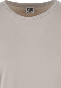 Lys grå T-shirt lavet af blødt stof, med rund halsudskæring og et mærke med "Urban Classics" og størrelse XS indeni kraven.