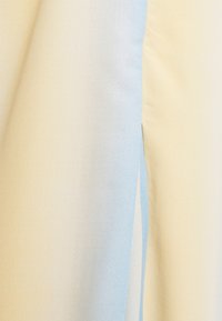 Telas texturizadas en crema y azul claro con una abertura vertical que revela material en capas debajo.