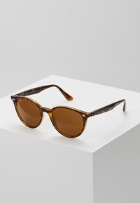 Ochelari de soare tortoiseshell marron cu lentile rotunde și mânere subțiri, având accente mici din metal argintiu și un finisaj lustruit.