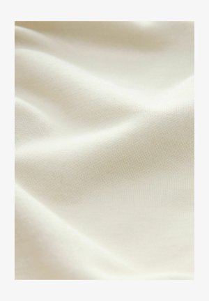 Tissu beige clair avec une surface lisse, légèrement texturée, montrant de douces plis et un ombrage subtil dans le matériau.