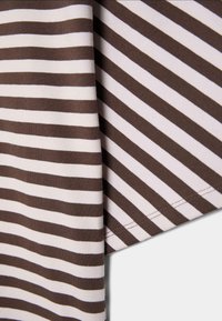 Brunt og hvidt stof med horisontale og diagonale striber og synlig syning langs kanten.