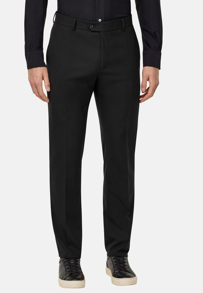 Pantalons noirs avec une coupe slim, dotés d'un devant plat, de passants de ceinture et de poches latérales. Associés à des baskets noires pour un look moderne.