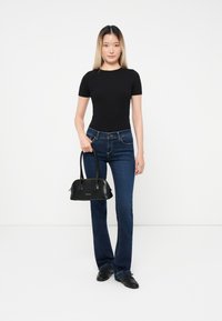Black fitted t-shirt, dark blue flared jeans, and a small black handbag with a glossy texture and dual handles. Simple design, no visible patterns.