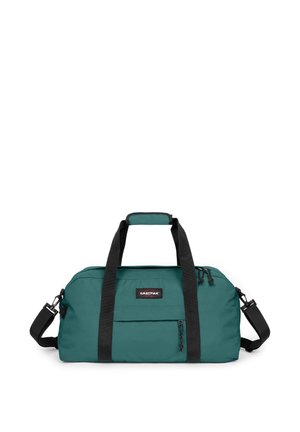 Sac de sport bleu sarcelle avec poignées noires et poche avant zippée, marque Eastpak, avec bandoulière réglable sur fond blanc.