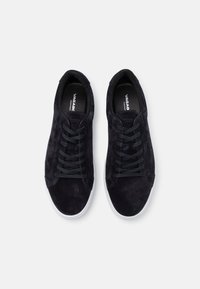 Tenisi negri din suede, cu vârf rotund, având șireturi plate negre, talpă din cauciuc alb și branding subtil pe interior.