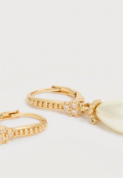 Gyldne øreringe med perlet struktur og små klare ædelsten, med en hængende dråbeformet hvid perle charm.