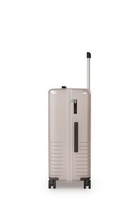 Hard-shell koffer in lichtbeige met verticale ribbelstructuur, een driecijferige combinatieslot en een uitschuifbare aluminium handgreep. Vier wielen voor wendbaarheid.
