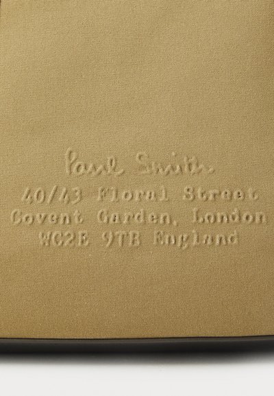 Tissu beige avec un texte en relief détaillant "Paul Smith" et une adresse : 40/43 Floral Street, Covent Garden, Londres, WC2E 9TB, Angleterre.