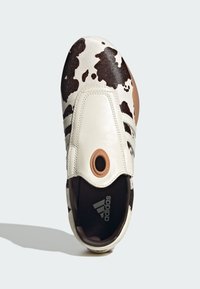 White leather shoe with brown cowprint pattern, round brown accent on top, and black interior. Features three side stripes.