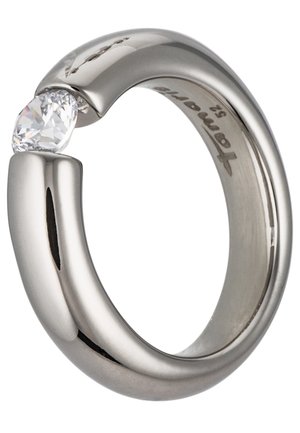 Bague en métal argenté avec une unique pierre précieuse ronde et claire tenue entre deux extrémités, avec une gravure à l'intérieur de l'anneau.