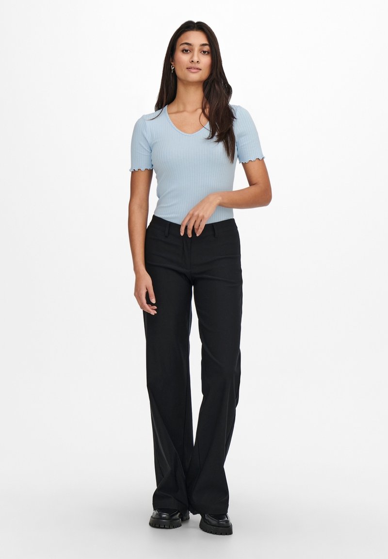 Light blue ribbed short-sleeve top with scalloped edges paired with black wide-leg trousers and chunky black shoes.