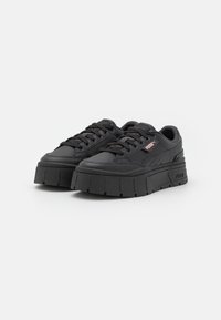Schwarze Plattform-Sneaker mit einem strukturierten Lederobermaterial, dicke Gummisohle, runder Zehenform und Schnürung. Besitzt auffällige Markenkennzeichnung an der Seite.