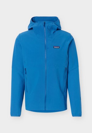 Sinine kapuutsiga jope esilukuga, kahe lukuga küljetaskuga ja väikese Patagonia logoga vasakul rinnal.