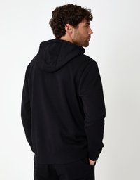 Schwarzer Kapuzenpullover mit lockerer Passform, gerippten Bündchen und Saum. Weiche Textur, minimalistisches Design, Rückansicht mit sichtbarer Kapuze.