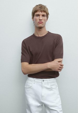Braunes kurzärmliges T-Shirt aus Baumwolle, kombiniert mit weißen Jeans aus Denim. Schlichtes Design, Rundhalsausschnitt, lässige Passform, keine Muster oder Grafiken.