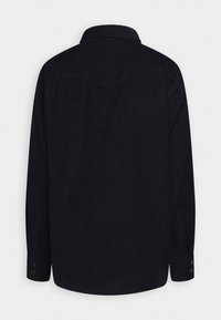 Chemise noire à manches longues avec poignets boutonnés vue de dos, avec un empiècement pointu sur les épaules.