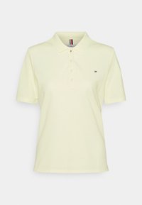 Polo in cotone giallo chiaro con colletto classico, patta con tre bottoni e un piccolo logo sul lato sinistro del petto. Maniche corte.