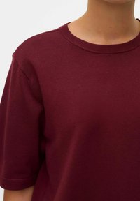 Top a maniche corte in magenta lavorato a maglia con scollatura a girocollo rigata e una texture liscia, caratterizzato da dettagli di cucitura discreti sulle spalle.