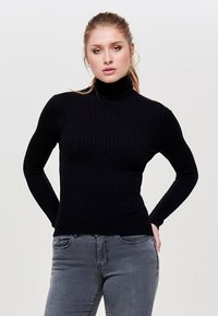 Schwarzer gerippter Rollkragenpullover in einer taillierten Passform, aus strukturiertem Stoff, kombiniert mit grauen Jeans. Schlichter und monochromatischer Stil.
