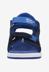 Sandalo blu con strap in Velcro, materiali in suede e rete, design aperto davanti, suola bianca e accenti blu a contrasto. Logo del marchio visibile.