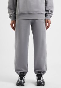 Grijze sweatpants met een relaxte pasvorm, ribbelboorden en een klein logo-opdruk. Gemaakt van een zachte, gestructureerde stof met zijnaads.