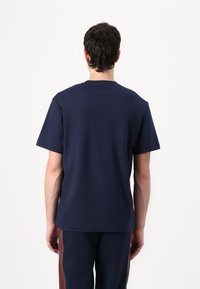 Ναυτικό μπλε βαμβακερό μπλουζάκι με στρογγυλή λαιμόκοψη και κοντά μανίκια, από τη πίσω πλευρά. Απλό ύφασμα χωρίς σχέδια ή αναφορές.