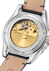 Reloj automático con caja de acero inoxidable plateada, fondo transparente y movimiento mecánico dorado. Correa de cuero marrón. 21 joyas.