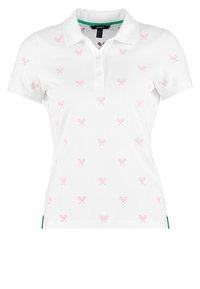 Vit polo-shirt med rosa tennisracketmönster, kort ärm, en treknappsdämpare och grön accent vid fållen. Mjuk bomullsmaterial.
