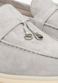 Light grey suede loafers featuring a bow detail and silver hardware accents. The design includes stitched edges and a contrasting soft sole.