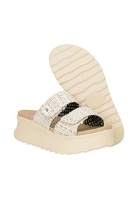 Sandalias de playa blancas con dos correas de tela, acentos texturizados en negro y una suela de plataforma en color crema con un patrón ondulado. Logo de la marca visible.