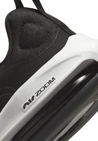 Schwarzer Sportschuh mit einer strukturierten Mesh-Oberfläche, weißem Zwischensohle und einem sichtbaren "Air Zoom"-Logo. Verfügt über eine abgerundete, gepolsterte Sohle.