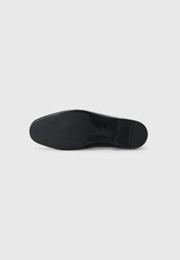Semelle de chaussure en cuir noir avec une texture lisse, bout arrondi et un léger talon. Présente une finition à motifs sur le dessous pour une meilleure adhérence.