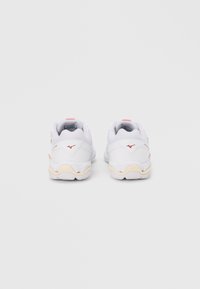 Valkoiset urheilukengät oransseilla yksityiskohdilla, kuvioidulla pohjalla ja pehmustetulla kauluksella. Kengissä on logo kantapäässä ja hengittävä kangas.